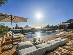 a swimming pool with couches and an umbrella at Casa Panorama in Illes Balears