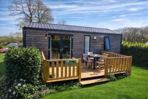 a small cabin with a deck and a table at Camping La sablière in Saint-Jans-Cappel