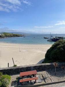a wooden bench sitting on a beach near the water at Beachview Rental in Clare Island