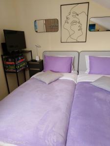 two beds with purple and white pillows in a bedroom at Apartman Cvita in Bilice
