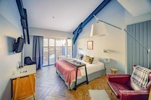 a bedroom with a bed and a tv and a couch at Le Florida Auberge contemporaine in Castéra-Verduzan