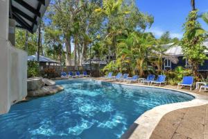 a swimming pool with blue chairs and trees at Absolute Beachfront Palm Cove Apt Sleeps 4 in Palm Cove