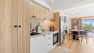a kitchen with white cabinets and a dining room with a table at Absolute Beachfront Palm Cove Apt Sleeps 4 in Palm Cove