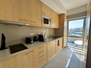 a kitchen with wooden cabinets and a sink and a microwave at Antas Balcony Studio by LuxiStay in Porto +19 photos