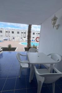 a white table and chairs on a patio with a pool at Aguazul 120 in Tías