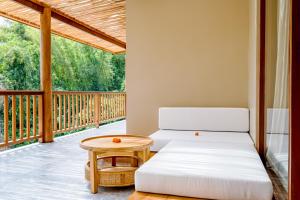 a room with two beds and a table on a porch at Villa Canopy - Spacious Luxury 4BR Villa Near Nuanu and Luna Beach Club in Tabanan