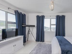 a bedroom with a bed and a tv and windows at Poolstreet 18 in Agulhas