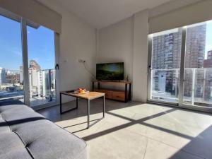 a living room with a couch and a tv and windows at Espectacular departamento en Palermo in Buenos Aires