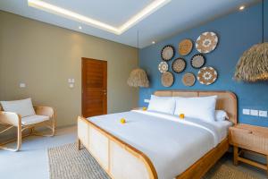 a bedroom with a large bed and a chair at Villa Canopy - Spacious Luxury 4BR Villa Near Nuanu and Luna Beach Club in Tabanan