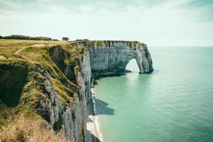 an arch in the side of a cliff next to the ocean at Chambre d' hôtes Etigue - Etretat in Les Loges