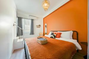 a bedroom with orange walls and a bed with a basket on it at Industrial Loft Sukhumvit 3-Bedroom Designer House - 2 Min to BTS Bang Chak in Bangkok