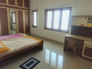 a bedroom with a bed and a desk and windows at Three bedroom villa in Mysore