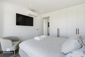 a white bedroom with a bed and a chair at Mara Etxea - Villa with pool e Ocean View in Ericeira