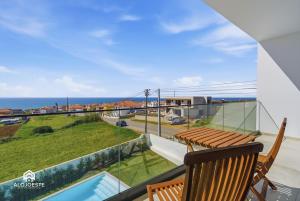 a balcony with a table and chairs and the ocean at Mara Etxea - Villa with pool e Ocean View in Ericeira