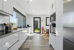a kitchen with white cabinets and a dining room at Mara Etxea - Villa with pool e Ocean View in Ericeira