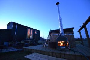 a tiny house with a fireplace on a deck at Isabelle Shepherd's hut in Hethersett