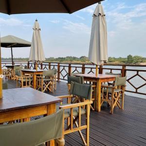 a group of tables and umbrellas on a deck at Emms Cubango Ecological Camp in Divundu