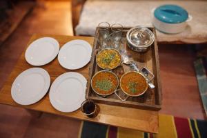 a table with white plates on a wooden table at Top Mountain Mist Near Jibhi in Banjār