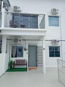 a white house with a bench in front of it at D'Suriah Homestay in Tanjung Karang