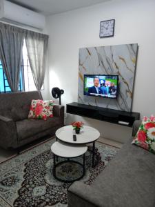 a living room with a couch and a table and a tv at D'Suriah Homestay in Tanjung Karang