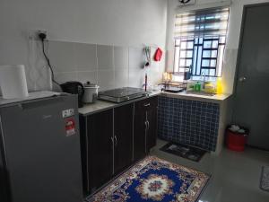 a small kitchen with a refrigerator and a window at D'Suriah Homestay in Tanjung Karang