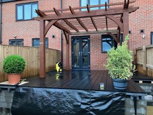 a wooden pergola with two potted plants on a deck at Waverley 3-Bed Springfields House in Rotherham