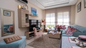 a living room with a blue couch and a tv at Cosy appartement in Bouznika