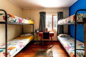 a room with two bunk beds and a desk at Zoete Inval Travelers Lodge-Backpacker Loft in Hermanus