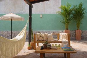 a hammock and a bench with a table and an umbrella at Casa Magu Merida in Mérida