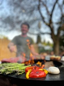 a man standing in front of a grill with vegetables at Glamping Les Arpents Verts in Yvoir