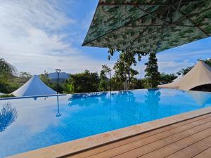 a swimming pool with an umbrella and tents at Seawind Cloudcrest Resort in Semporna