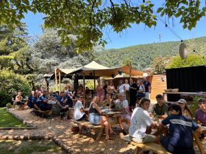 a group of people sitting at tables in a garden at Glamping Les Arpents Verts in Yvoir