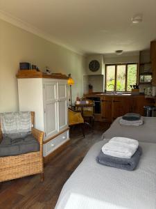 a bedroom with two beds and a kitchen with a table at Just a Minim - quaint studio in beautiful rural retreat in Rushford