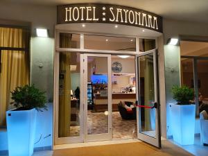 a hotel singalore entrance with two potted plants in front at Hotel Sayonara in Milano Marittima