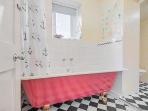 a red tub in a bathroom with a checkered floor at 4 Bed in Wigton oc-sz384 in Bothel +14 photos