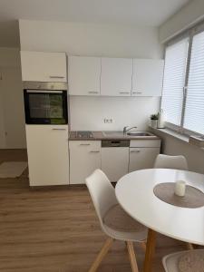 a white kitchen with a white table and chairs at Bauna Suites & Apartments in Baunatal