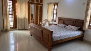 a bedroom with a bed and a table and windows at Serenity Villa in Mysore