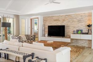 a living room with white furniture and a brick wall at Clos du Littoral by Sealodge Mauritius in Grand-Baie