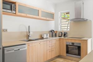 a kitchen with wooden cabinets and a sink at Clos du Littoral by Sealodge Mauritius in Grand-Baie +64 photos
