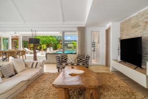 a living room with a couch and a tv at Clos du Littoral by Sealodge Mauritius in Grand-Baie