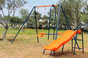 a playground with an orange slide in a park at Villa Aria in Kampos Paros