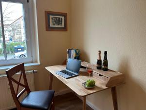 a table with a laptop and two bottles of wine at Hochwertige Wohnung im EG- Meißen zum Genießen in Meißen