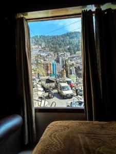a view of a city from a bedroom window at Golden Glow Stays in Shimla