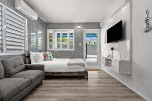 a bedroom with a bed and a couch and a tv at La Balandra Luxury Stays in Dorado