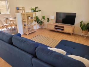 a living room with a blue couch and a tv at G & R Beach Cottage in Warnbro
