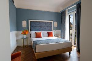 a bedroom with a bed with blue walls and orange pillows at Rivoli Boutique Hotel in Florence +67 photos