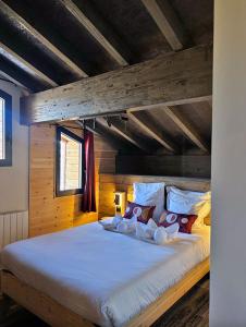 a large bed in a room with a wooden ceiling at Hôtel Chalet Sainte-Anne in Condamine-Châtelard