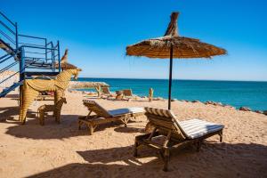 a beach with chairs and an umbrella and the ocean at Loft Beachfront Bungalow with Private Beach in Dakhla