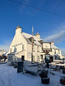 a building with boats in front of it in the snow at Crown and Anchor Inn in Findhorn +56 photos