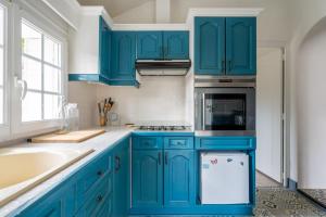 a kitchen with blue cabinets and a sink at Maison semi-troglo - Proche Chenonceaux - Amboise - La Caburoche de Charlemagne in Civray-de-Touraine